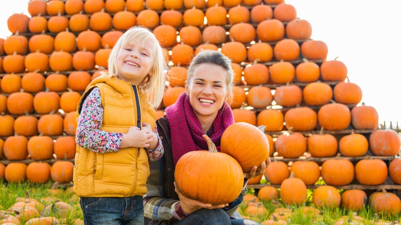 Mom and daughter smiling with pumpkins